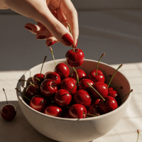 Modèle : Mystique
Prompt : Un bol en céramique rempli de cerises mûres, posé sur une surface douce sous une lumière naturelle chaleureuse. Une main féminine délicate, aux ongles rouges brillants, s’avance pour saisir doucement une cerise par la tige. La composition est intime et vibrante, avec des tons rouges profonds contrastant avec la céramique lisse et discrète. Les textures réalistes capturent l’éclat du fruit, la courbe des doigts et la chaleur subtile d’un moment d’été nostalgique.
